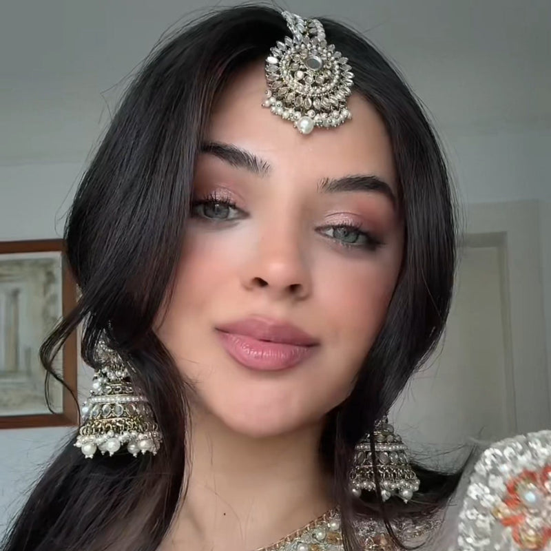 Woman wearing traditional jewelry and a decorated outfit indoors